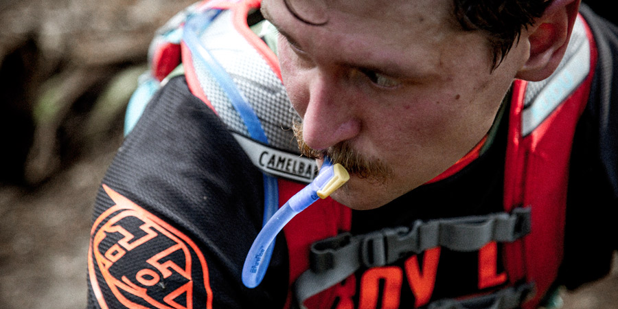 a sweaty biker drinking from the hose of hydration reservoir