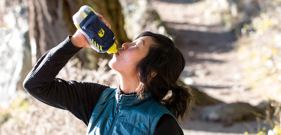 trail runner drinking from a handheld water bottle