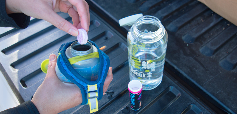 trail runner placing an electrolyte tablet into their water bottle