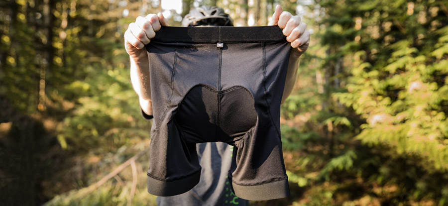 a biker holding up a pair of biking shorts with built-in chamois