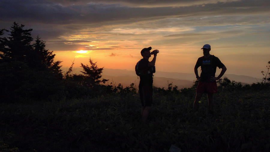 two trail runners taking a hydration break as the sun sets