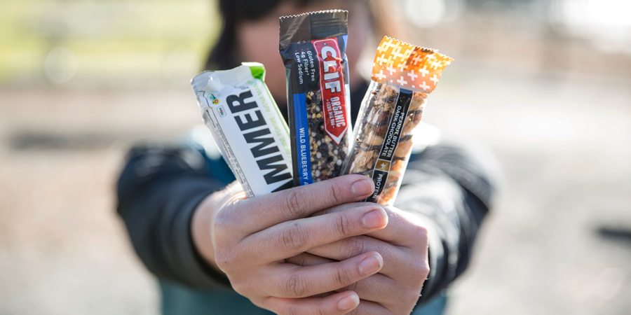 a trio of energy bars in hand