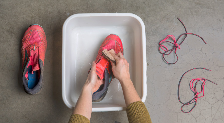 scrubbing the uppers of dirty running shoes with soap and water