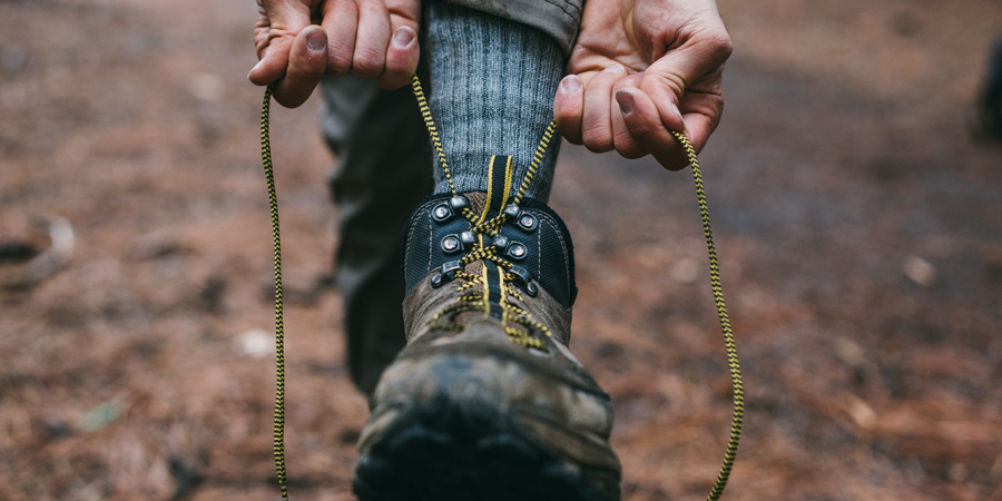 a hiker tying the laces of their hiking boots