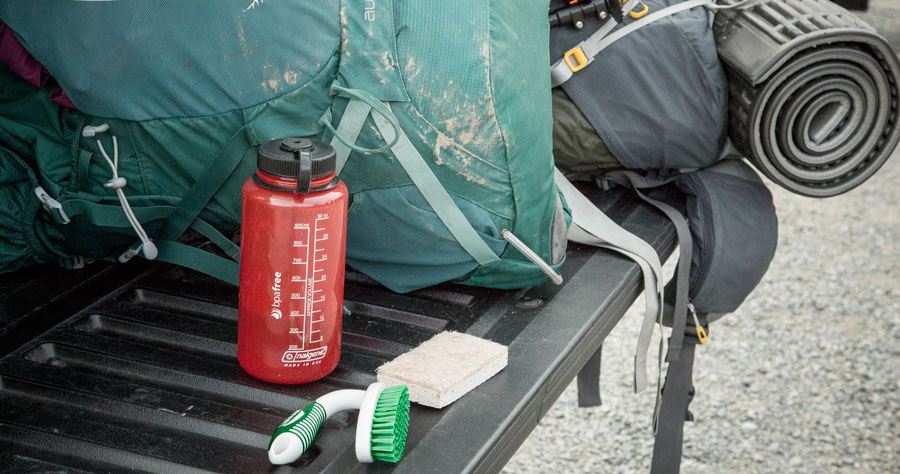 a dirty backpack and cleaning supplies on a tailgate