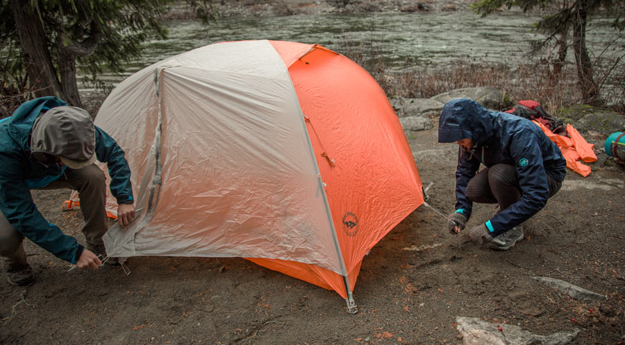 fitnessinf Expert Advice: How to Go Backpacking in the Rain - two backpackers setting up their tent in the rain