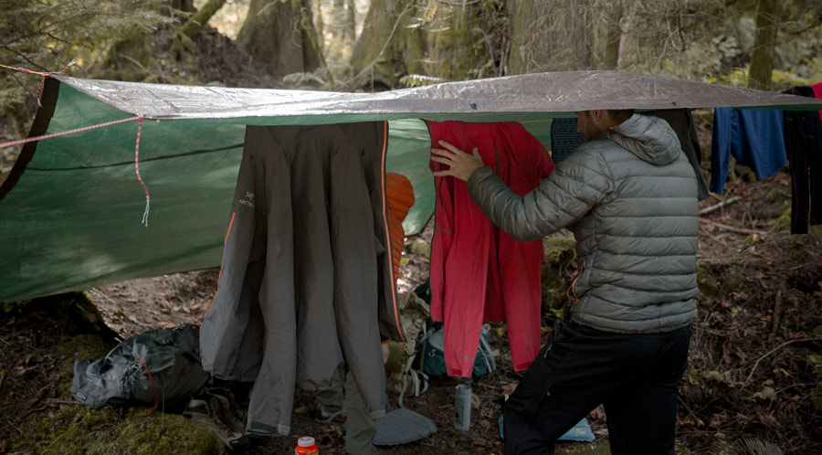 fitnessinf Expert Advice: How to Go Backpacking in the Rain - a backpacker setting up a clothes line to dry out wet clothes in the wet conditions