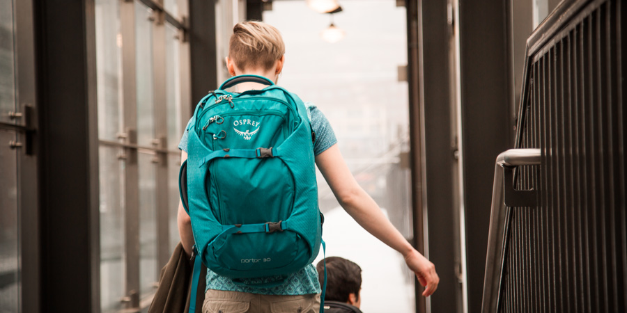a traveler ascending stairs at the station with their travel backpack on